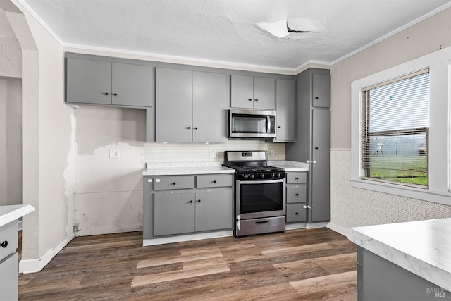 kitchen with stainless steel appliances, gray cabinets, dark wood finished floors, and light countertops