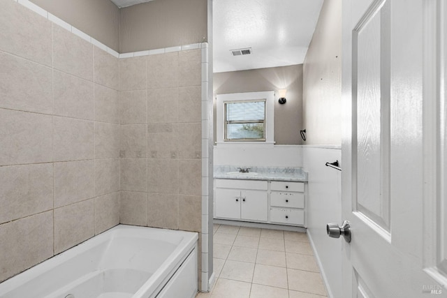 bathroom with tile patterned floors, visible vents, a bathtub, and vanity