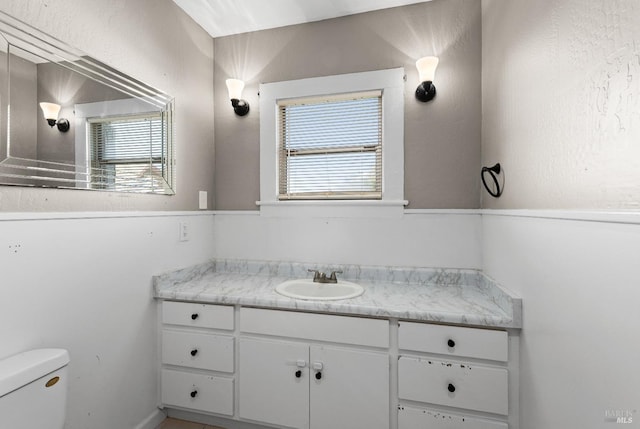 bathroom featuring a healthy amount of sunlight, toilet, and vanity