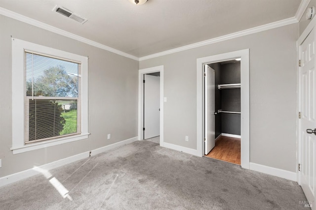 unfurnished bedroom featuring baseboards, visible vents, carpet floors, and crown molding