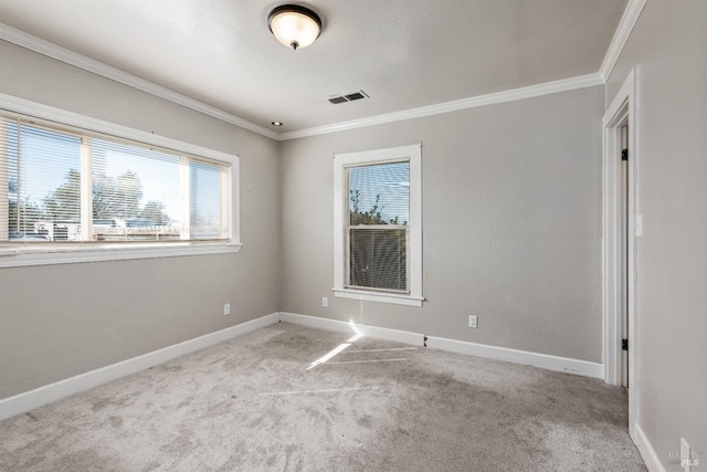 spare room with ornamental molding, visible vents, carpet flooring, and a healthy amount of sunlight