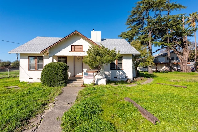 bungalow-style home featuring a shingled roof, crawl space, stucco siding, a chimney, and a front yard