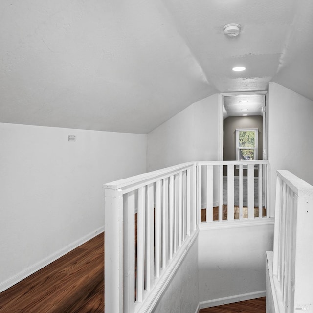 hall featuring an upstairs landing, lofted ceiling, baseboards, and wood finished floors