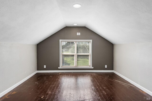 bonus room featuring a textured ceiling, hardwood / wood-style floors, vaulted ceiling, and baseboards