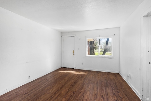 unfurnished room with baseboards and dark wood-type flooring