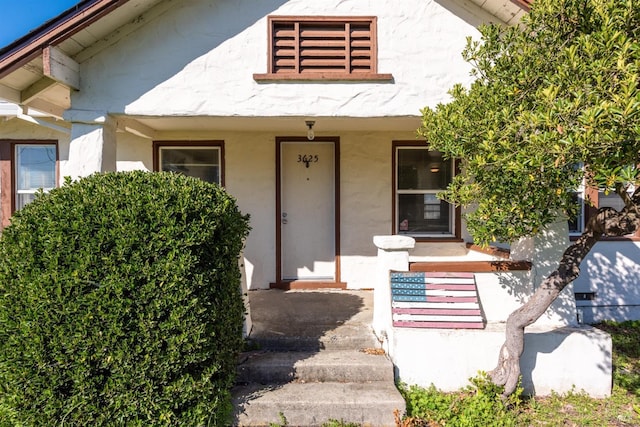 view of exterior entry featuring a porch and stucco siding