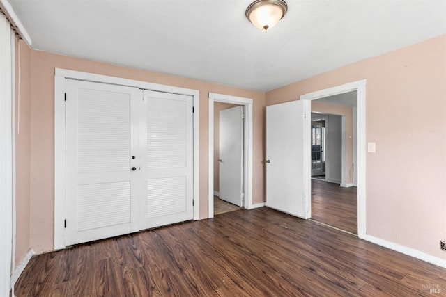 unfurnished bedroom with a closet, dark wood-style flooring, and baseboards