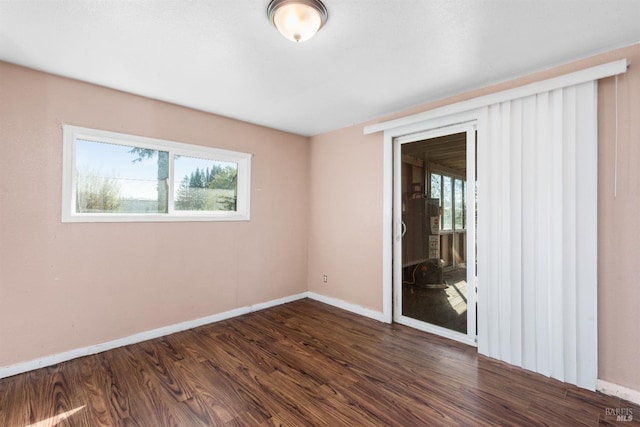 unfurnished room with baseboards and dark wood finished floors