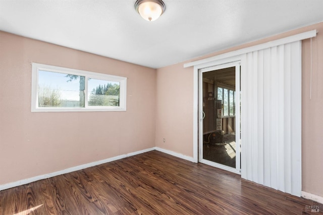 spare room featuring baseboards and dark wood-type flooring