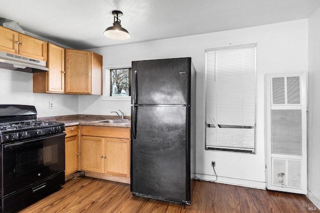 kitchen featuring a sink, under cabinet range hood, a heating unit, dark wood-type flooring, and black appliances