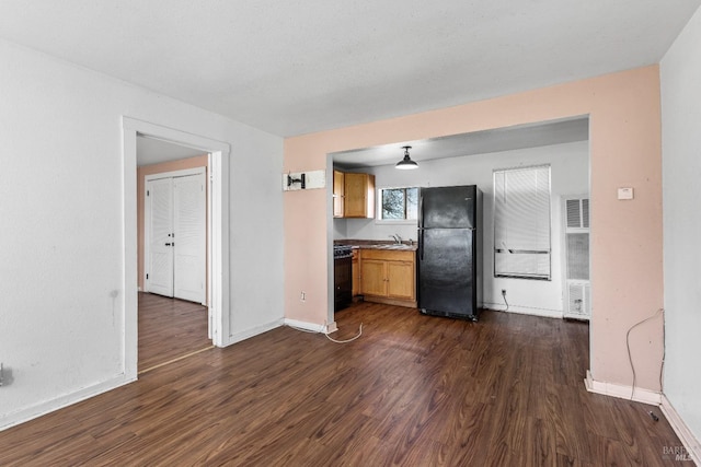 interior space featuring a sink, visible vents, baseboards, dark wood-style floors, and black appliances