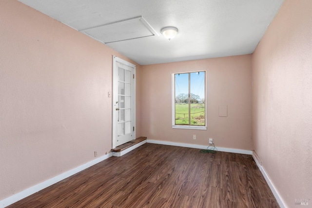 spare room featuring baseboards and dark wood-type flooring