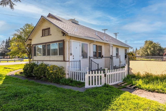 view of front facade featuring stucco siding, fence, a shingled roof, and a front lawn