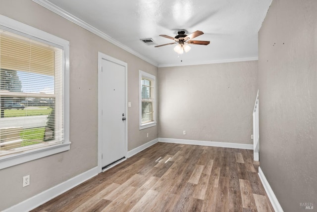 entryway with crown molding, visible vents, baseboards, wood finished floors, and a ceiling fan