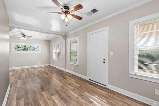 foyer entrance featuring ornamental molding, ceiling fan, wood finished floors, and visible vents
