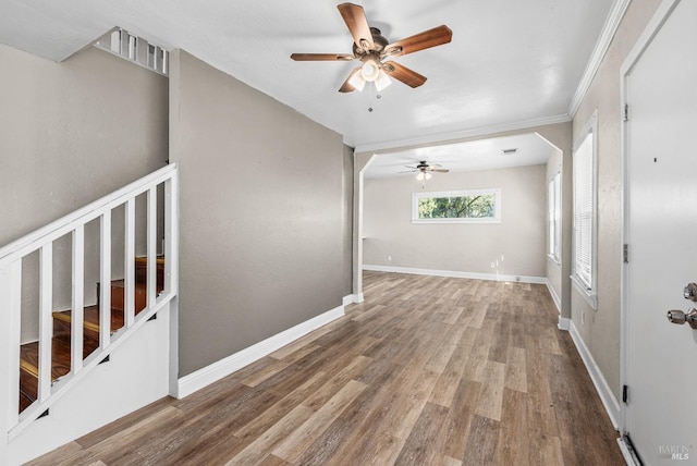 empty room featuring visible vents, baseboards, a ceiling fan, wood finished floors, and crown molding