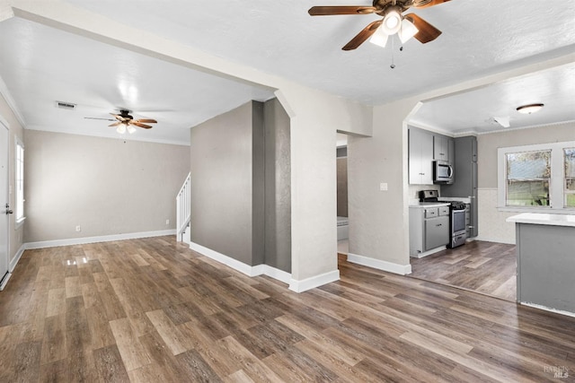 unfurnished living room featuring baseboards, visible vents, wood finished floors, and a ceiling fan