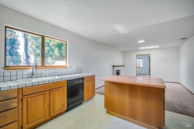 kitchen featuring a sink, open floor plan, a brick fireplace, dishwasher, and light floors