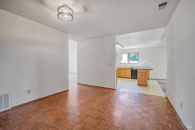 empty room with a textured ceiling, a sink, and visible vents