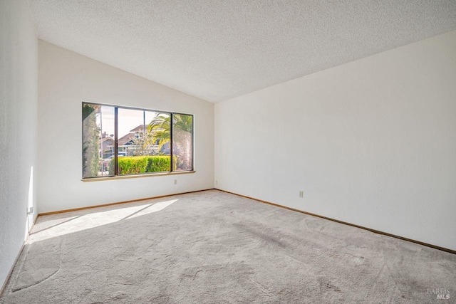 carpeted spare room with vaulted ceiling, a textured ceiling, and baseboards