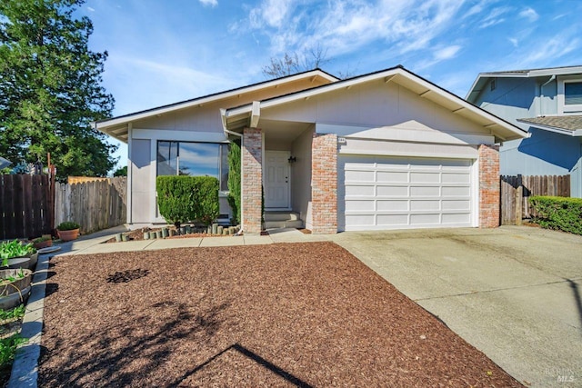 view of front of property with a garage, driveway, fence, and brick siding