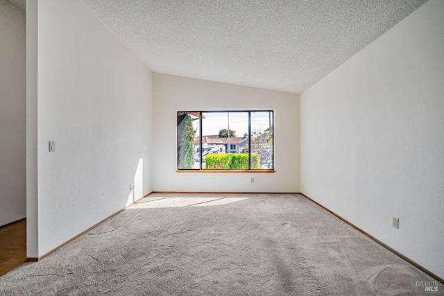 carpeted spare room with lofted ceiling, baseboards, and a textured ceiling