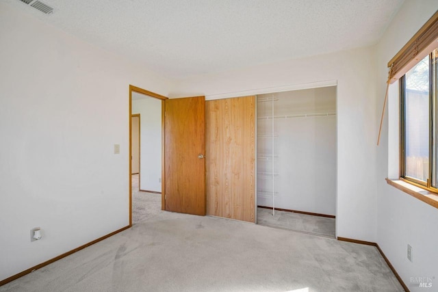 unfurnished bedroom with carpet, a closet, visible vents, and a textured ceiling