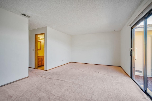 empty room featuring carpet floors, visible vents, a textured ceiling, and baseboards