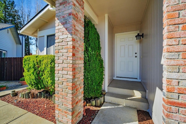 property entrance with brick siding and fence