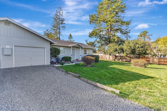 view of front of property featuring an attached garage, a front yard, fence, and gravel driveway