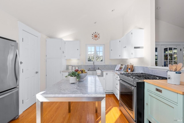 kitchen with a kitchen island, appliances with stainless steel finishes, light wood-style floors, white cabinetry, and a sink