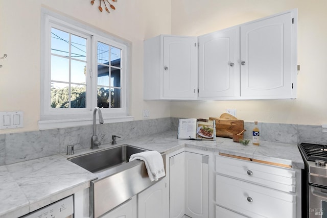 kitchen with a sink, dishwashing machine, white cabinets, and light countertops