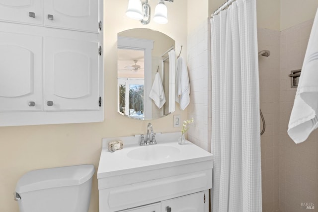 full bath with toilet, a stall shower, vanity, and a ceiling fan