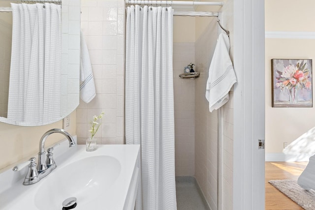 bathroom featuring wood finished floors, a sink, and a shower stall