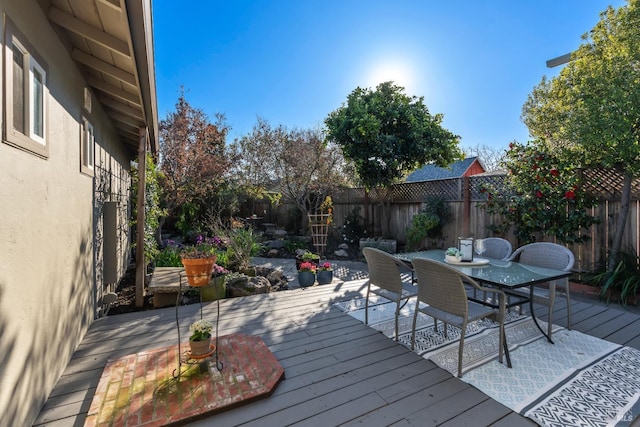 wooden terrace with outdoor dining area and a fenced backyard