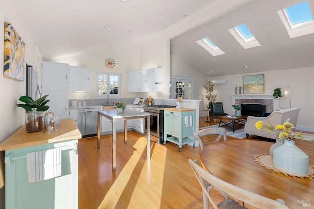 dining space featuring high vaulted ceiling, a brick fireplace, a wall unit AC, and light wood-style flooring