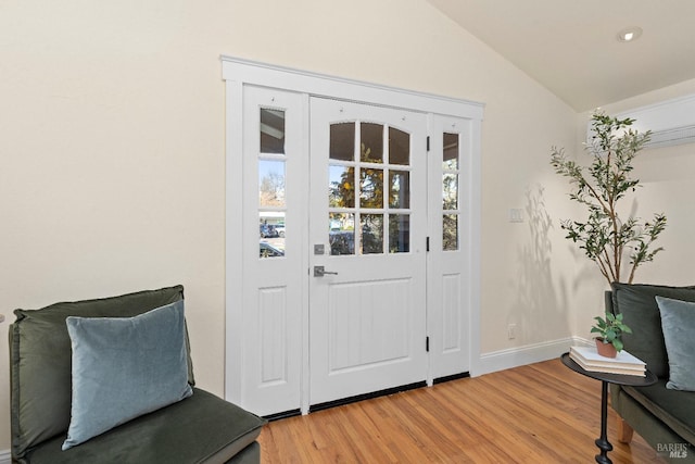 interior space with light wood-style floors, vaulted ceiling, and baseboards