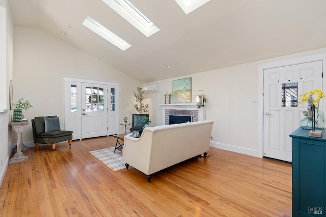 living area featuring a skylight, a fireplace, light wood finished floors, high vaulted ceiling, and a wall mounted air conditioner