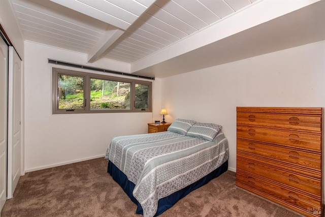 bedroom featuring baseboards, wooden ceiling, beam ceiling, carpet floors, and a closet