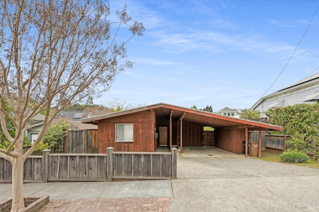 view of front of property featuring fence, an attached carport, and concrete driveway