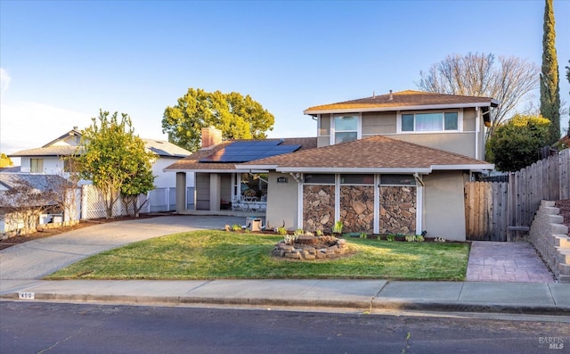 traditional-style home with stucco siding, fence, a front lawn, and solar panels