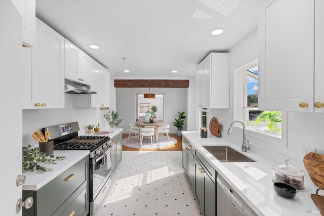 kitchen featuring light countertops, white cabinets, stainless steel gas stove, a sink, and under cabinet range hood