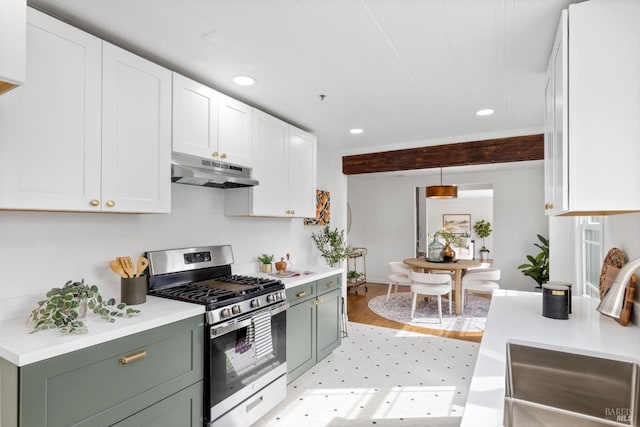 kitchen featuring stainless steel gas range, a sink, under cabinet range hood, and green cabinets