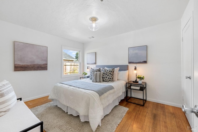 bedroom featuring a textured ceiling, wood finished floors, and baseboards