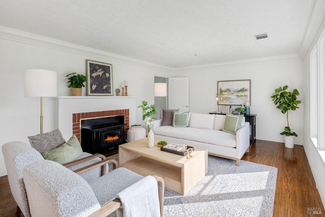 living area featuring a fireplace, wood finished floors, visible vents, baseboards, and ornamental molding