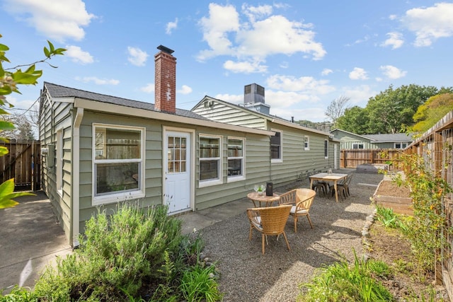 back of property featuring a chimney, a patio area, and a fenced backyard