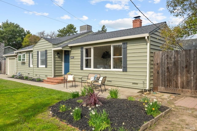 rear view of property with a yard, an attached garage, fence, and a shingled roof