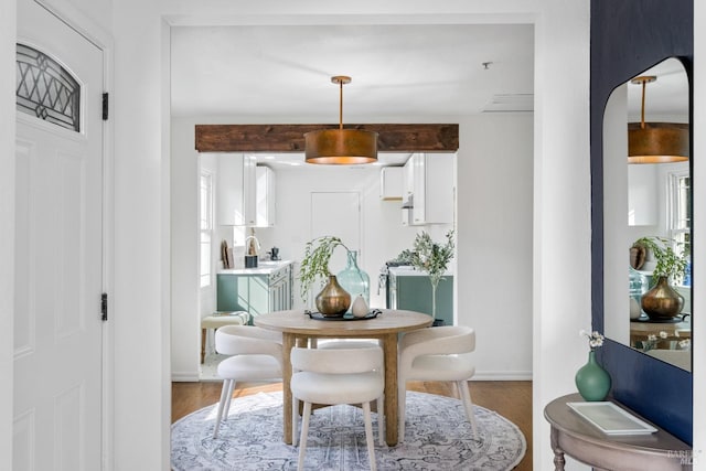 sitting room with baseboards, beamed ceiling, and light wood-style floors