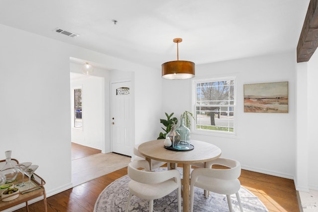 dining area featuring baseboards, visible vents, and wood finished floors