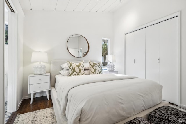 bedroom with a closet, wooden ceiling, baseboards, and wood finished floors